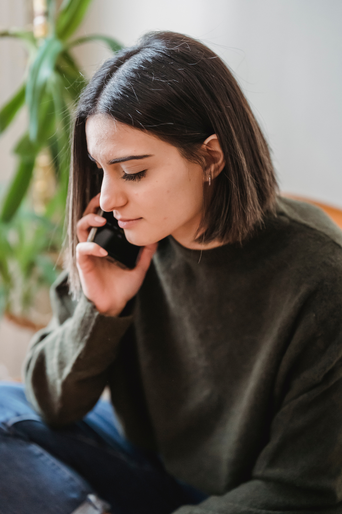 Thoughtful female in chair having phone call at home